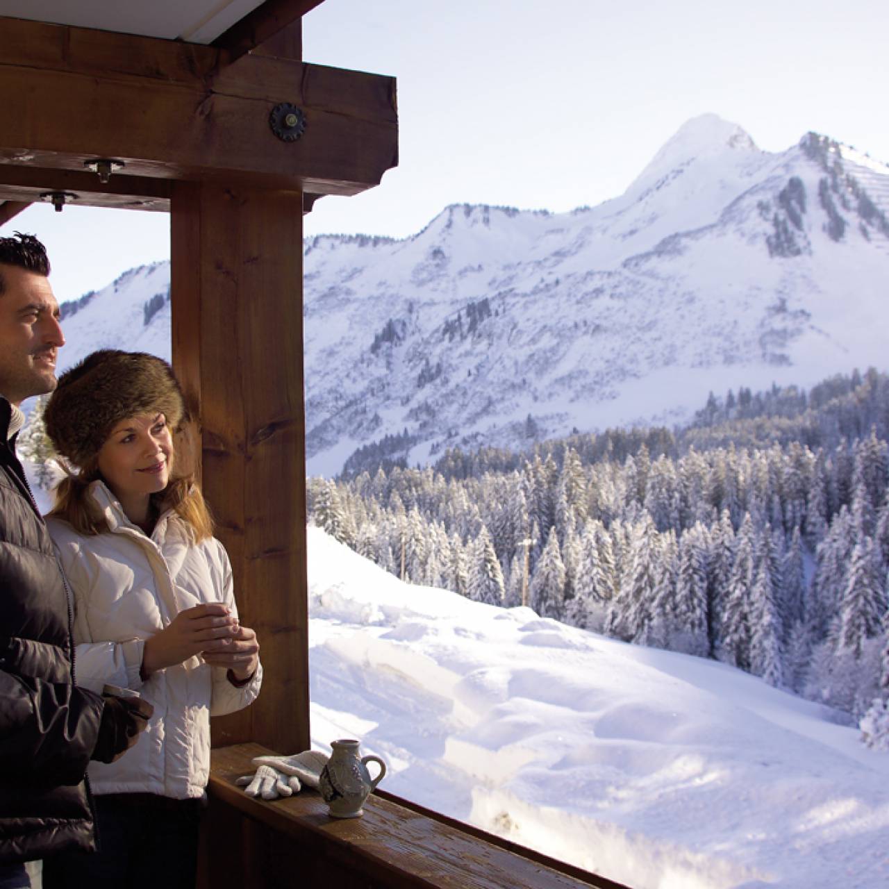 Pärchen genießt verschneite Berglandschaft auf dem Zimmerbalkon