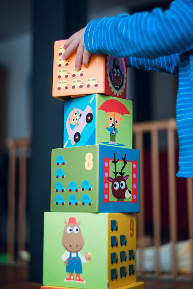 Kind baut einen Turm aus Bauklötzen im Spielzimmer